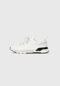 Sneaker bianco con parte superiore in mesh, accenti neri e lacci riflettenti. Presenta il marchio "VERSACE JEANS COUTURE" lungo il lato della suola.