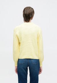 Ανοιχτό κίτρινο πλεκτό πουλόβ ερ με ριμπ υφή και άνετη εφαρμογή. Διαθέτει μακριά, ελαφρώς φουσκωτά μανίκια και στρογγυλή λαιμόκοψη.