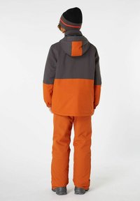 Orange und graue isolierte Winterjacke mit Kapuze, ausgestattet mit elastischen Bündchen und einem kontrastierenden Design. Kombiniert mit passenden orangenen Hosen.