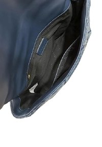 Interno di una borsa in pelle blu con una texture liscia, dotato di una fodera nera, una tasca con zip e un piccolo scomparto.