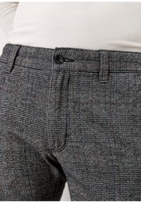 Szare spodnie w kratę wykonane z teksturowanej tkaniny, z zapięciem na guzik i kontrastującymi detalami w szwie.