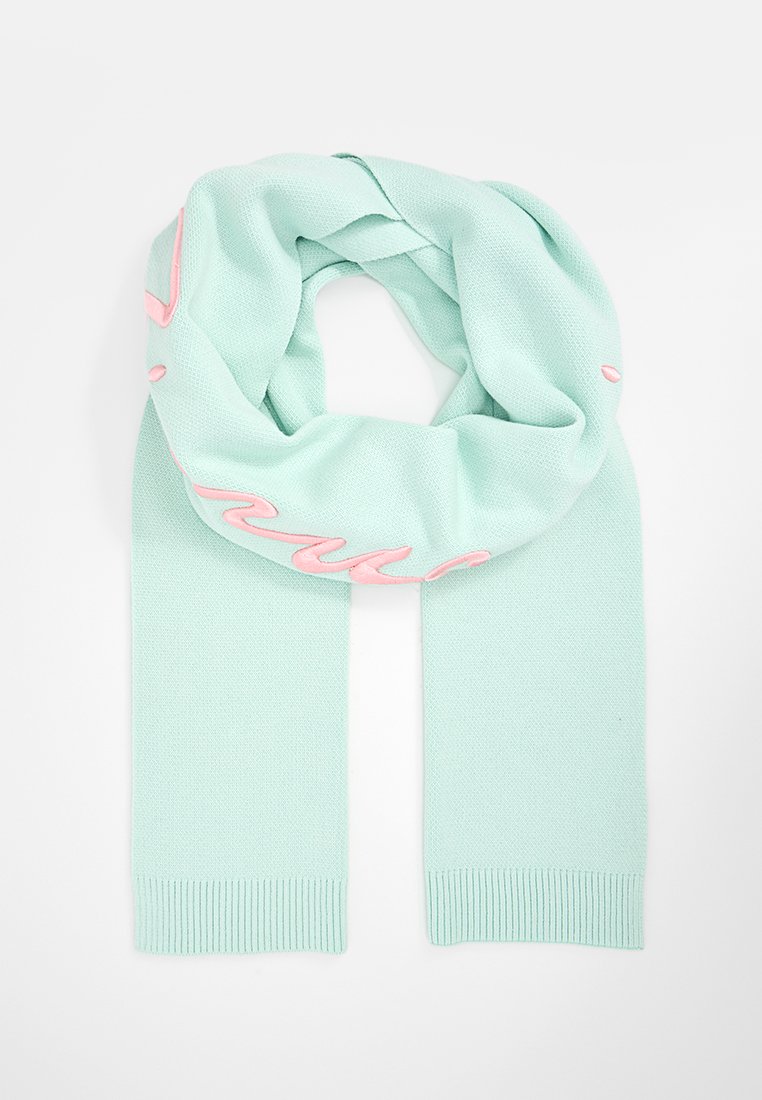 Mintgrüne gestrickte Schal mit gerippten Enden und pinkem Schriftzug auf einer Seite, die ein weiches, strukturiertes Finish zeigt.