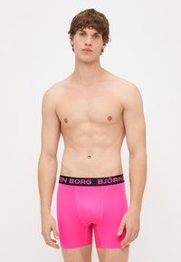 Ehedalt roa värvi bokserid musta elastse vööga, millel on embosed tekst "BJÖRN BORG." Sile, veniv materjal, liibuv disain.