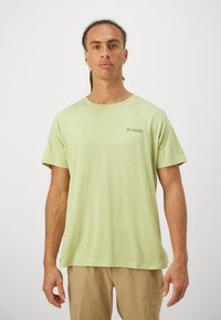 Tricou din bumbac verde deschis, cu guler rotund, mâneci scurte și un mic logo negru pe pieptul stâng. Textură netedă.