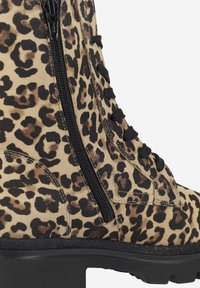 Stivaletti alla caviglia con stampa leopardata, caratterizzati da una tomaia texturizzata, lacci neri, zip laterale e suola nera spessa.