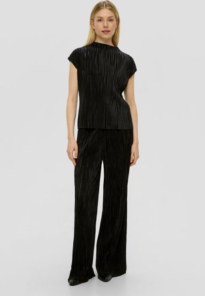 Haut noir plissé avec manches courtes associé à un pantalon noir plissé assorti. Les deux pièces présentent un tissu fluide et texturé avec des jambes larges.