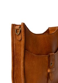 Brun læder tote bag med en tekstureret overflade, der har en frontlomme, en løkke til påhæftning og en flad lukning med en knapdetalje.