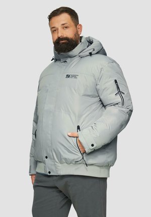 Lichtgrijze pufferjack met een hoge kraag, ritszakken en elastische manchetten. Kenmerkt zich door branding op de borst en een gestructureerde afwerking.