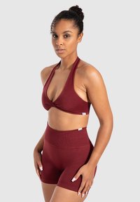Bordeaux atletisch crop top met halterontwerp en klapsluiting, gecombineerd met hoge taille shorts. Gemaakt van rekbare, gladde stof.