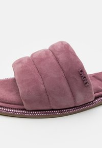 Rosa mockaskinnsandal med tre breda, vadderade remmar och en pärlade detalj på sulan. DKNY-logotyp präglad på sidan.