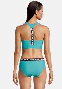 Türkiser Sport-Bralette mit Racerback-Design, ausgestattet mit einem schwarzen FILA-Logo-Träger und passenden Bikini-Hosen mit einem schwarzen Bund.