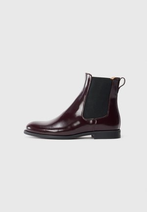 Glänzender dunkelburgunder Chelsea-Stiefelette mit schwarzem elastischem Seitenteil, abgerundeter Spitze, niedrigem Absatz und Zuglasche auf hellgrauem Hintergrund.