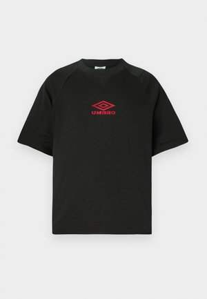 Crna majica kratkih rukava s okruglim izrezom s crvenim Umbro logotipom centriranim na prsima, na običnoj bijeloj pozadini.