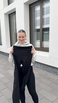 Fekete leggings, egy személy által tartva, rugalmas anyagból készültek, sima textúrával. A dizájn magasan elhelyezett derékpántot és látható logók nélküli kialakítást tartalmaz.