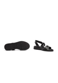 Sandales en cuir noir avec deux larges lanières accentuées de métal, un design à bride arrière et une semelle en caoutchouc texturée.
