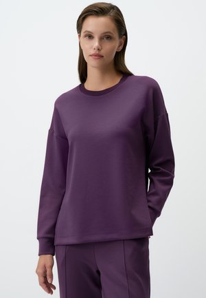Sweatshirt violet à manches longues en tissu doux, avec un col rond et une coupe décontractée aux épaules tombantes.
