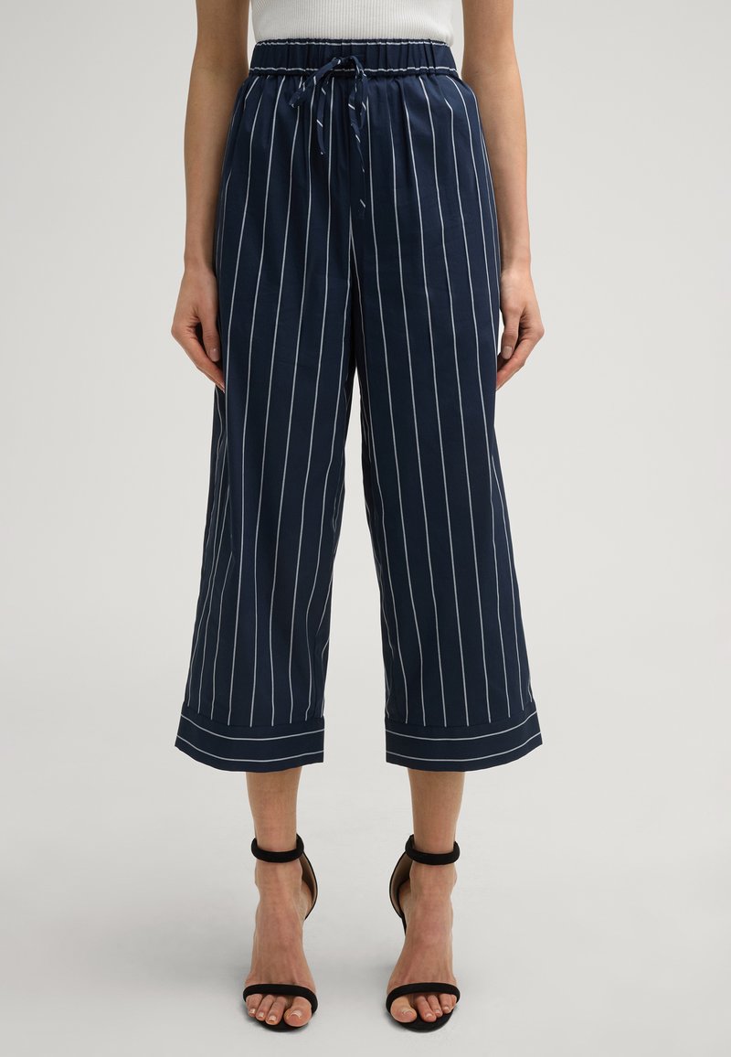 Pantaloni ampi blu navy con strisce verticali bianche, dotati di vita elastica e dettaglio con fiocco, con orlo a risvolto.