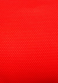 Tecido texturizado vermelho com um pequeno padrão em relevo que oferece aderência. Superfície lisa com um acabamento ligeiramente refletor. Adequado para várias aplicações.