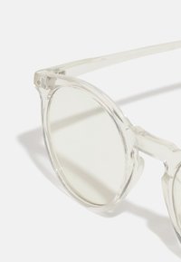 Klare acetat solbriller med runde linser, der har et minimalistisk design og en glat tekstur. Karakteristiske brede stænger og subtile detaljer.