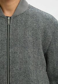Halli hall, puhvaga vooder, soonikuga krae ja esiseep. Materjal näib tekstuurne ja sobib kehasse.