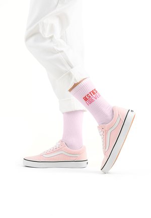 Rosa Leinenschuhe mit weißen Akzenten, kombiniert mit helllila gerippten Socken, die roten Text "BESTIES FOREVER" tragen, getragen mit weißen Hosen.