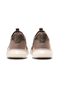 Hnědé pletené tenisky s hladkým hnědým koženým patním tabem, bílou mezipodešví a gumovou podrážkou, zdobené logem na patě a jemným prošitím.