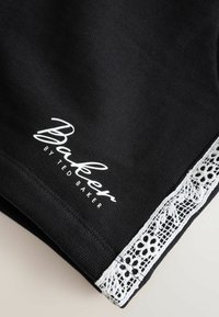 Material negru cu dantelă florală albă și logo-ul „Baker by Ted Baker” imprimat alb aproape de margine.