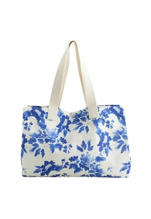 Sac cabas blanc avec motif floral bleu et larges anses en tissu beige.