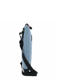 Schmale blaue Stofftasche mit schwarzem Tragegurt, oberem Verschlussdetail und einem kontrastierenden roten Akzent. Besitzt eine glatte Textur und ein minimalistisches Design.