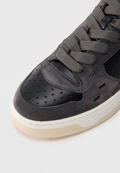 Γκρι σουέντ και μαύρο δερμάτινο αθλητικό παπούτσι με διάτρητες λεπτομέρειες, υφασμένα κορδόνια και ελαφριά λαστιχένια  σόλα. Διαθέτει στρογγυλεμένα άκρα στα δάχτυλα.