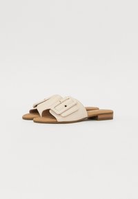 Sandali scivolati in pelle beige con una ampia fascia e dettaglio con fibbia rettangolare, tacco in legno basso e design con punta aperta.