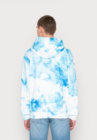 Felpa con cappuccio blu e bianca tie-dye con tasca a marsupio e cappuccio regolabile, caratterizzata da una morbida texture e una vestibilità rilassata.