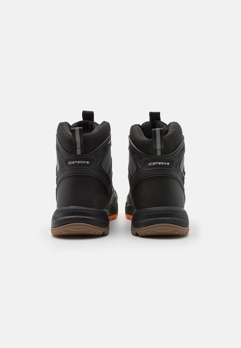 Para czarnych sportowych butów wysokich z brązowymi podeszwami, teksturowanym materiałem i uchwytami do zakupu, widziana z tyłu na białym tle.