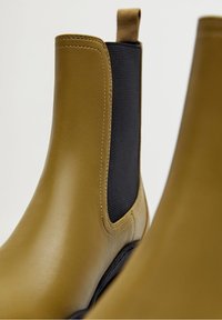 Bottines Chelsea en cuir marron clair avec panneaux latéraux élastiques noirs et languettes, présentées en gros plan sur un fond blanc.