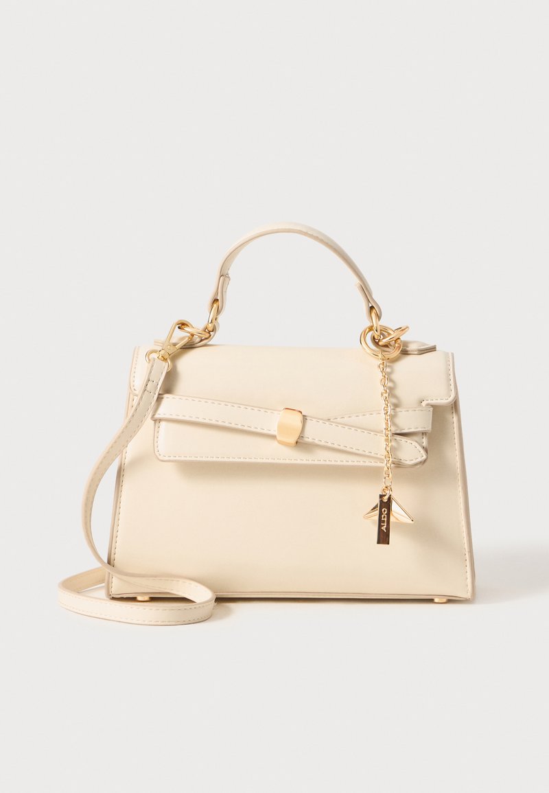 Bolso de mano color crema hecho de material sintético, con un asa superior, correa de hombro desmontable, detalle de lazo y herrajes en tono dorado.