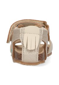Verstelbare kindersandaal in metallic goud, met een zachte leren band, een gestructureerde zool en een onderscheidend vingervormig accent op de achterkant.