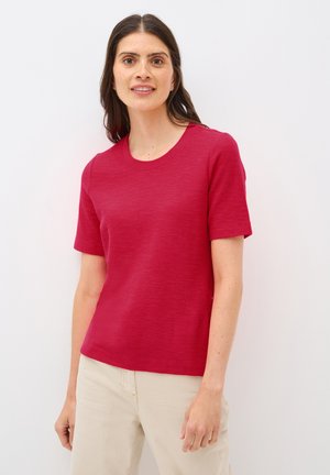 Top rosso a maniche corte realizzato in tessuto morbido e texturizzato, con scollatura rotonda. Presenta una vestibilità ampia e senza motivi o dettagli visibili.