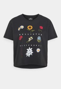 Černé bavlněné tričko s barevnými květinovými motivy. Na designu jsou sedmikrásky, slunečnice, růže a nápis "HOLLISTER CALIFORNIA". Zkrácený střih.