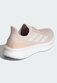 Roza pletena atletska tenisica s bijelim gumenim potplatom, tri bijele pruge i teksturiranim detaljima. Sadrži "ULTRABOOST" brand na boku.