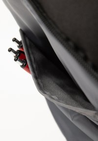 Zwarte nylon tas met een zak die gedeeltelijk rode pennen bevat; de zak heeft een zachte voering en is ontworpen voor gemakkelijke toegang.