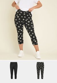 Svarta leggings med vitt och gult prästkragmönster, i medellång längd, tillverkade av stretchigt tyg, med elastisk midja, kombinerat med vita sneakers.