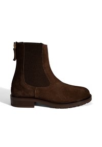 Bottines en daim marron avec des panneaux latéraux élastiques nervurés et une petite fermeture éclair, dotées d'une semelle plate et d'un design à bout rond.