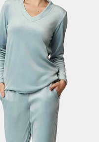 Lichtblauw loungewear set met een V-hals lange mouwen top en bijpassende broek, gemaakt van zachte, gladde stof met een ontspannen pasvorm.