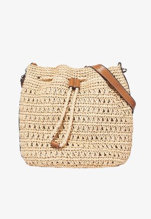 Woven straw bucket bag in beige with brown leather accents and a drawstring closure. Features a crossbody strap and textured surface.