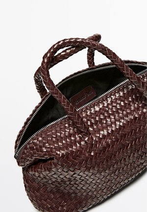 Geflochtene burgunderrote Lederhandtasche mit zwei geflochtenen Griffen und einem Reißverschluss. Das Innere ist mit einem dunklen Futter und einem Markenetikett ausgestattet.
