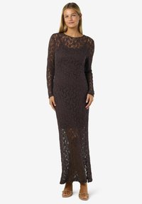 Dlouhé šaty z tmavé krajky, s dlouhými rukávy, kulatým výstřihem a poloprůhlednou sukní. Přetahují se přes tělo.