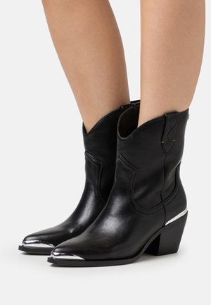 Black leather ankle boots with a pointed toe, metallic silver accents on the toe and heel, featuring a stitched design and a low block heel.