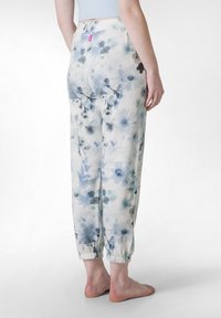 Floral-patterned trousers in light fabric, featuring shades of blue and green, with elastic cuffs and a small pink tag at the waist.