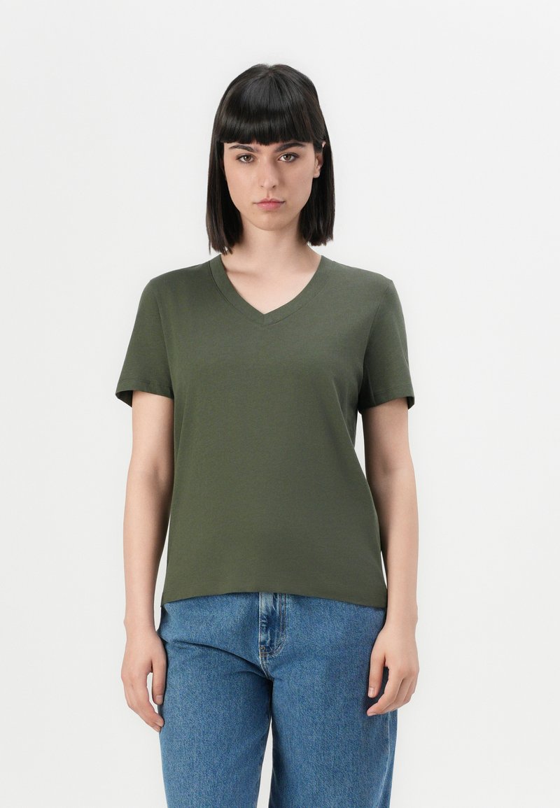Olivgrünes V-Ausschnitt-T-Shirt aus weichem Stoff, mit kurzen Ärmeln und lässigem Schnitt, kombiniert mit hochgeschnittenen blauen Jeans.