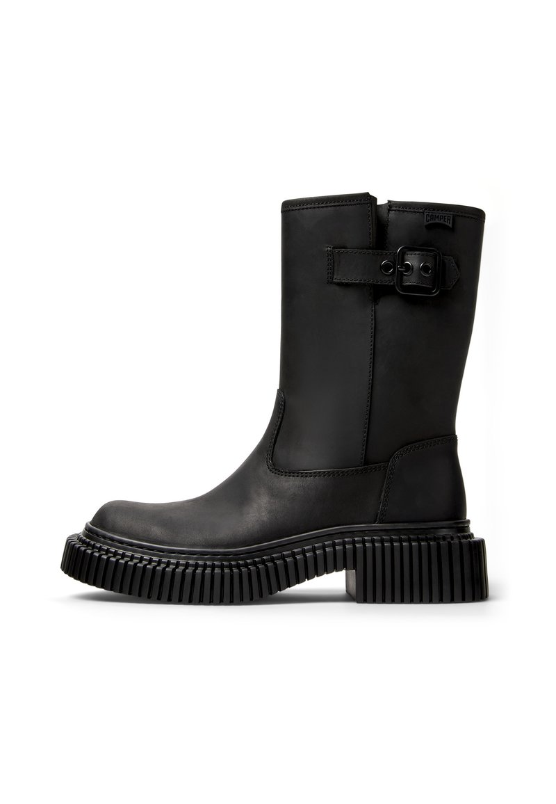 Black leather ankle boot with a rounded toe, a wide strap and buckle detail, and a thick, ridged rubber sole for traction.